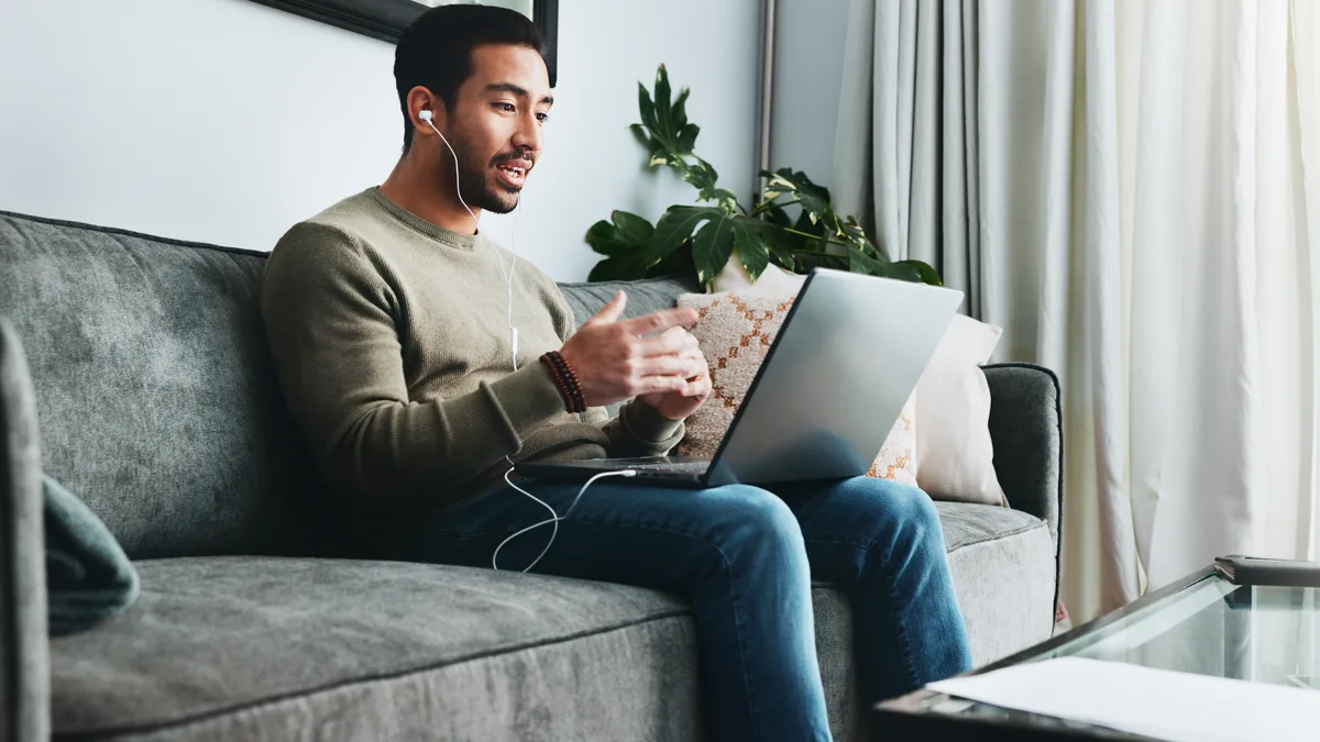 Man on couch with earbuds during an online therapy session